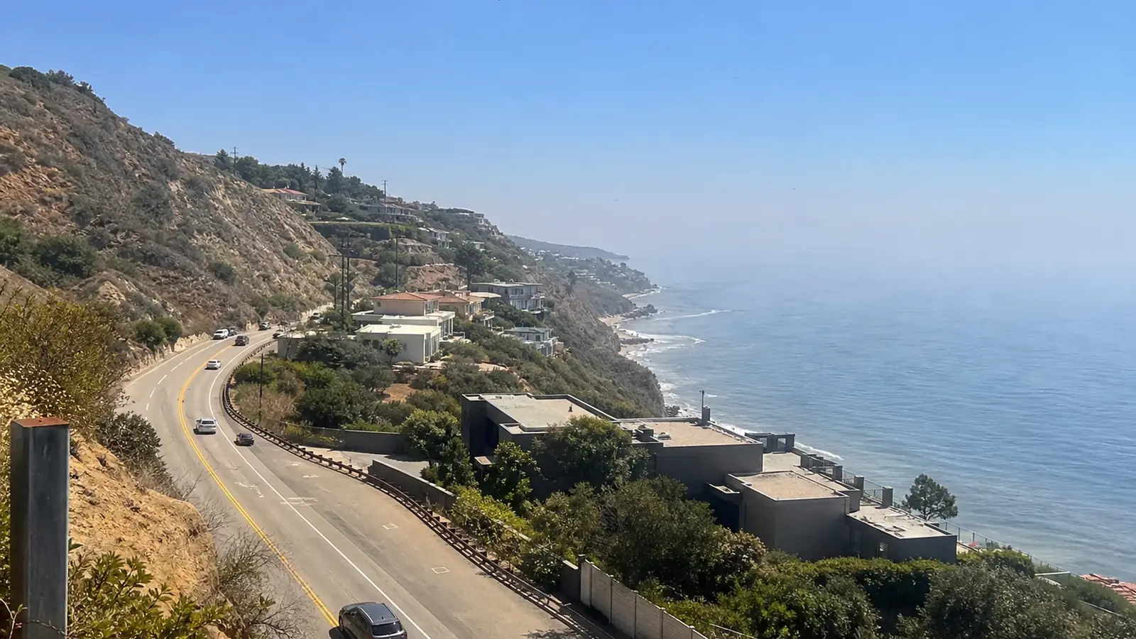 Pacific Coast Highway curving past hillside homes above the ocean in Malibu