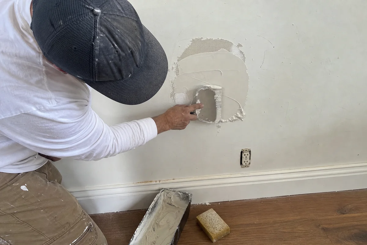 Patching a hole in drywall with joint compound at a Malibu home