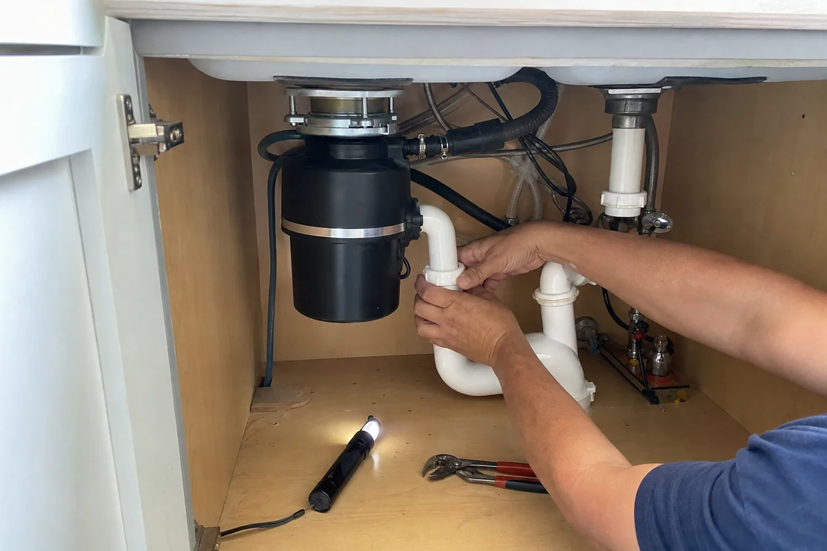 Installing a garbage disposal under a kitchen sink in a Malibu home